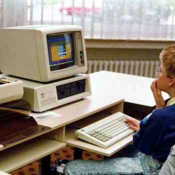 Young person looking at an early IBM PC-compatible.