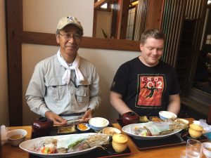 Me and a Japanese professor, each with a plate of transparent squid sashimi in front of us