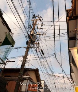 A mess of overhead power cables meeting at a street junction