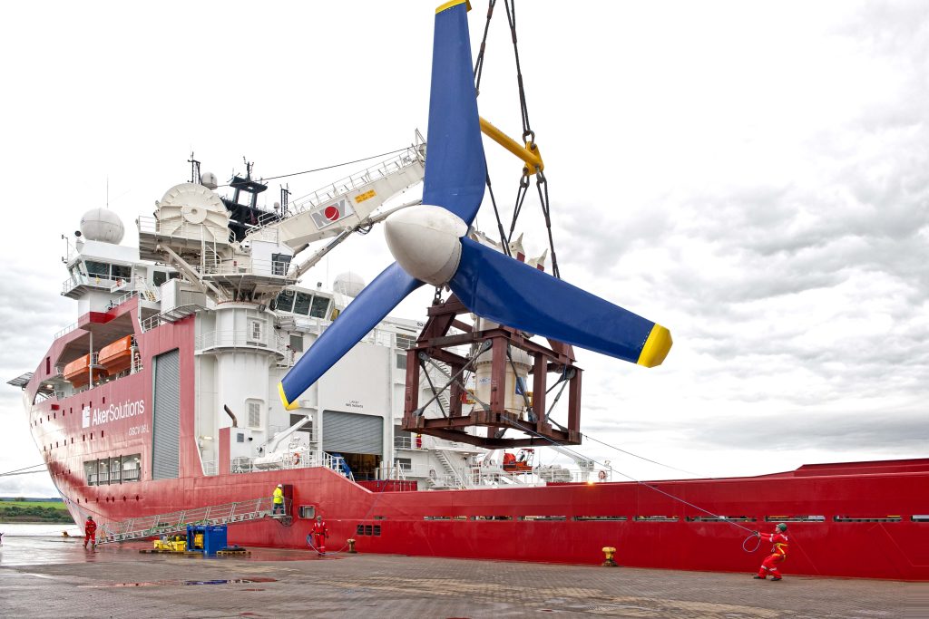 A ship's crane lifting a turbine from a quay