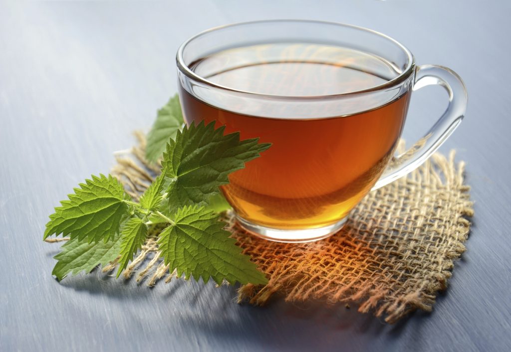 A glass cup of herbal tea, presented on a hemp mat.